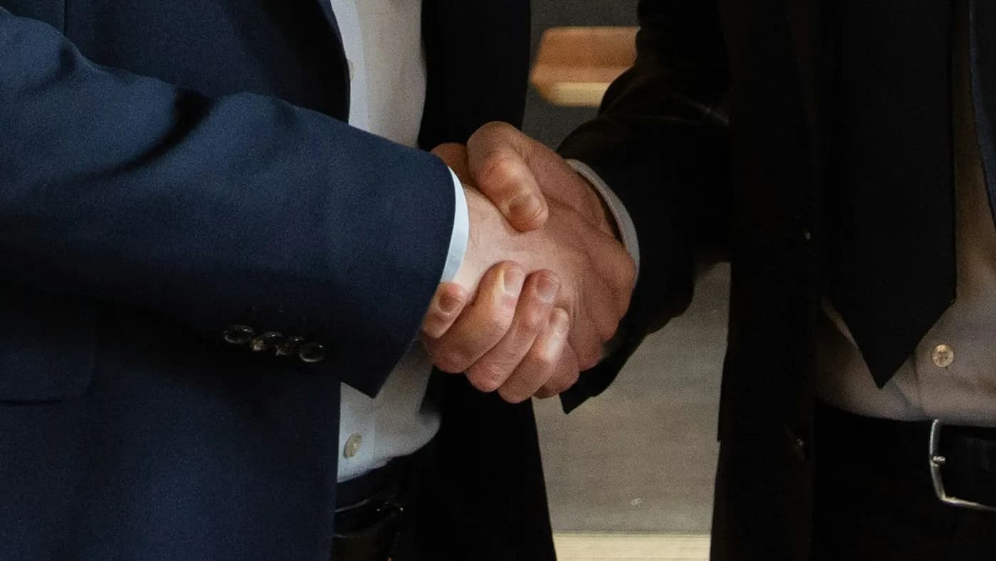 Aperto de mão entre duas pessoas de terno fechando uma parceria